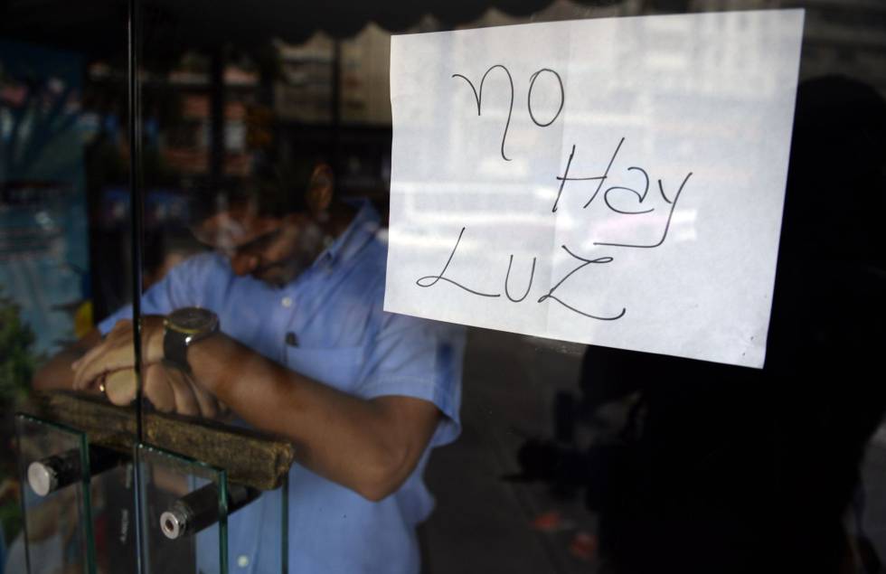 Un empleado, tras la puerta de un comercio cerrado en Caracas. 