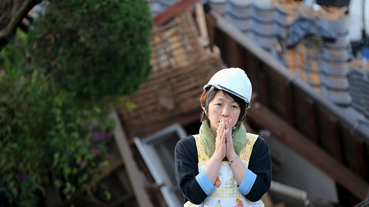 Una mujer frente a una vivienda en ruinas tras el terremoto de Mashiki, Kumamoto, Japón, 16 de abril de 2016.