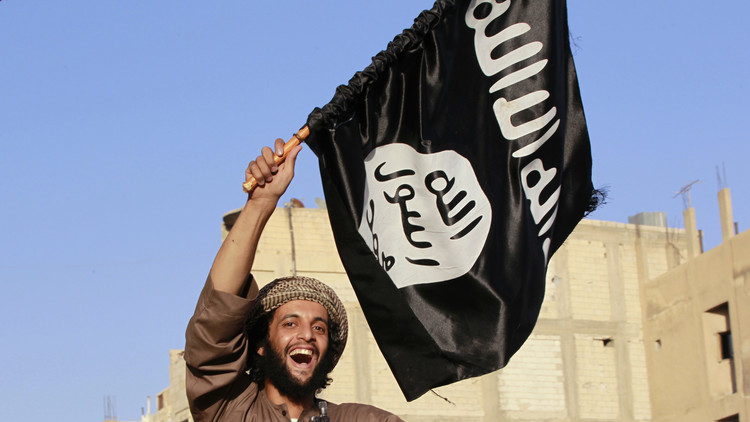 Un combatiente sostiene una bandera del Estado Islámico durante el desfile por las calles de una ciudad en la provincia de Al Raqa, al norte de Siria. 30 de junio de 2014.