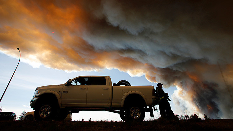 Gente esperando en un retén mientras el humo de los incendios forestales se eleva cerca de Fort McMurray, Alberta, Canadá. 6 de mayo de 2016.
