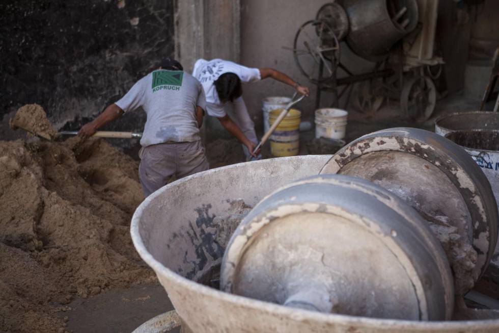 Obreros de la construcción preparan la mezcla con arena y cemento.