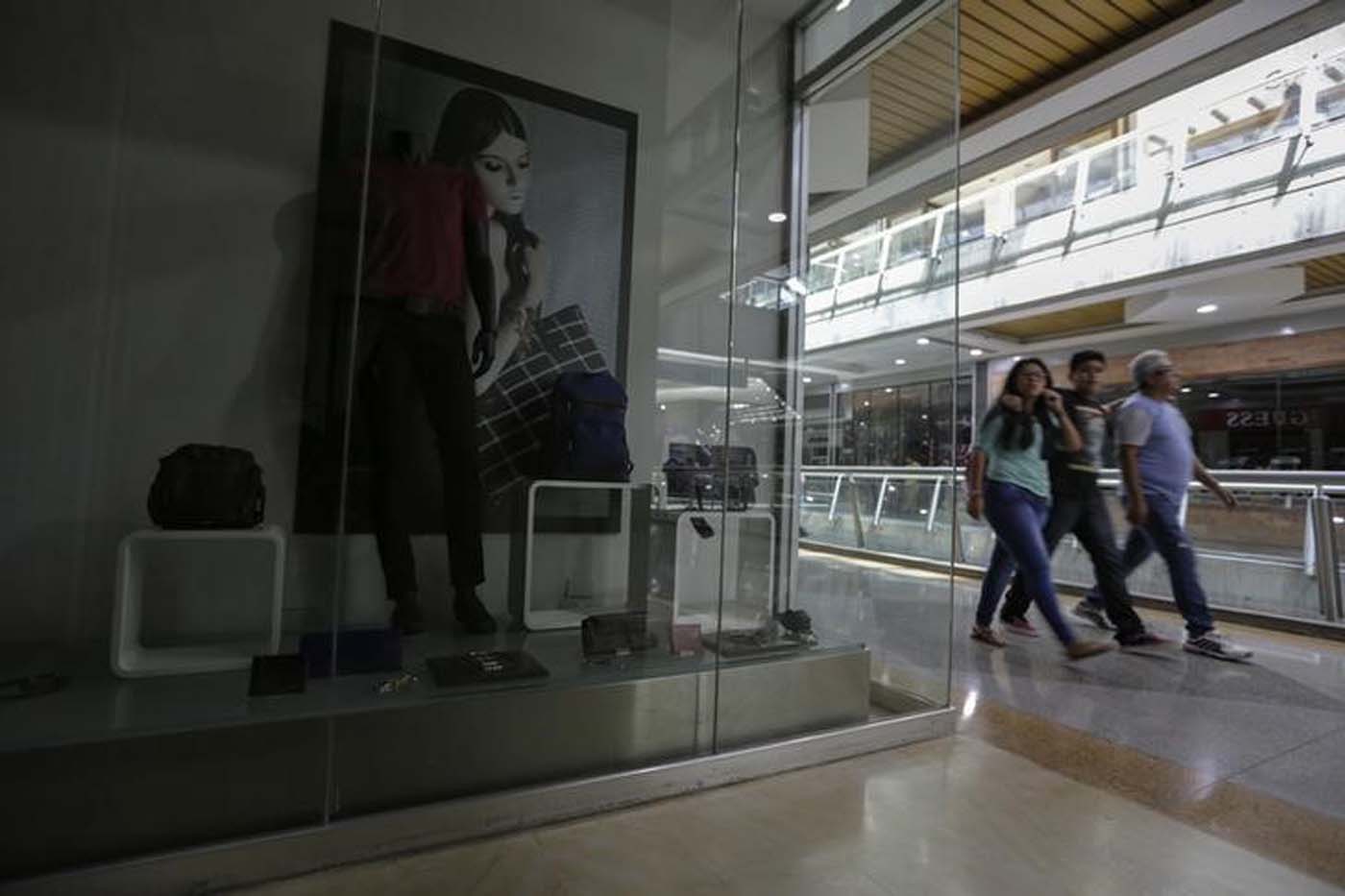 Unas personas pasan frente a una tienda cerrada en un centro comercial de Caracas, feb 10, 2016. Venezuela inició esta semana un plan de cortes de electricidad para restringir el consumo hasta que comience la temporada de lluvias, indispensables para que las plantas hidroeléctricas que generan un 60 por ciento de la energía del país recuperen su funcionamiento pleno. REUTERS/Marco Bello