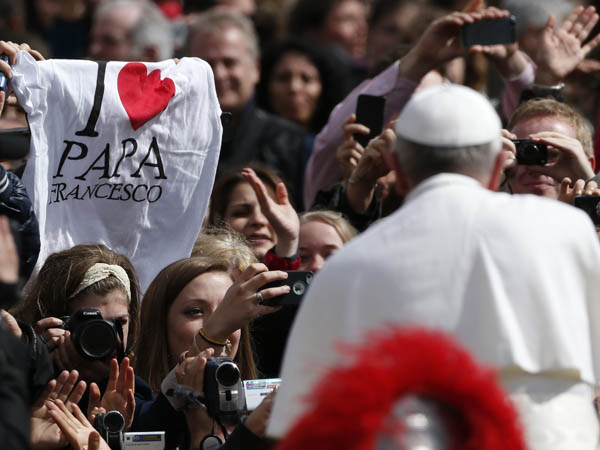 A faithful holds up a T-shirt as Pope Francis leaves at the end of the Easter mass in St. Peter's Square at the Vatican