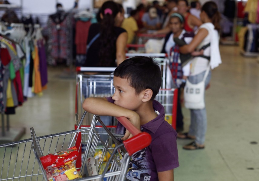 File photo of a boy waiting in a queue into a state-run supermarket in Caracas