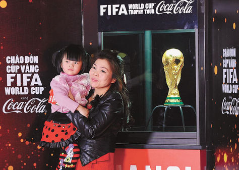 Gira. Arriba, una mujer de Vietnam y su hija posan con la Copa el 1 de este mes.