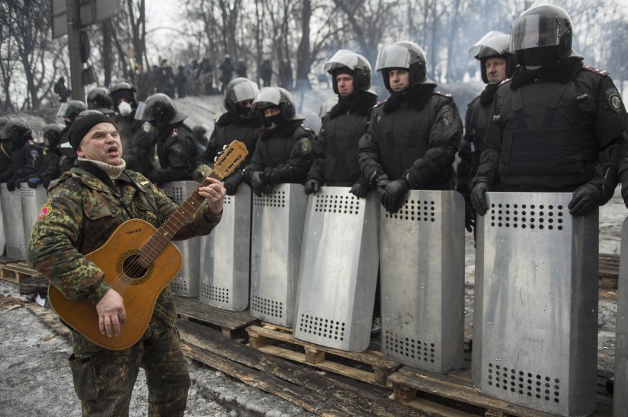 An anti-government protester plays the guitar in front of riot police at the site of clashes in Kiev