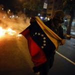 An opposition demonstrator runs with a flag during a protest against Nicolas Maduro's government in Caracas