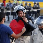 An opposition demonstrator gives a heart-shaped cutting to a police officer in Caracas
