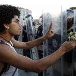 An opposition demonstrator gives flowers to a police as they block the city's main highway in Caracas