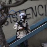 A national policeman walks past a graffiti reading 'Resistance' during anti-goverment protests at Altamira square in Caracas