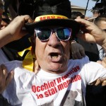 A protester is restrained outside the Sacred Family Foundation, where former Italian PM Berlusconi will serve part of his one-year tax fraud sentence by doing community service with the elderly, as he arrives in Cesano Boscone