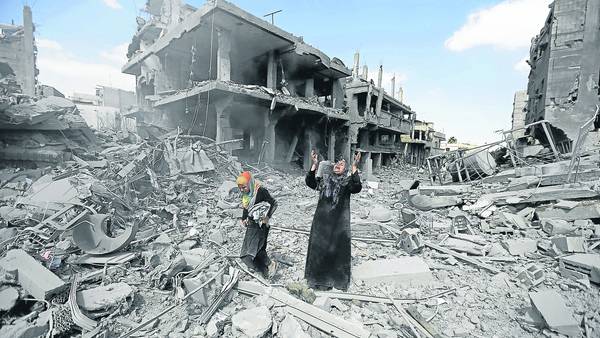 Clamor, incredulidad. La mujer alza los brazos cuando advierte los daños causados por los bombardeos al lugar donde vivía con su familia en Beit Hanun, en el norte de la Franja de Gaza. /AFP