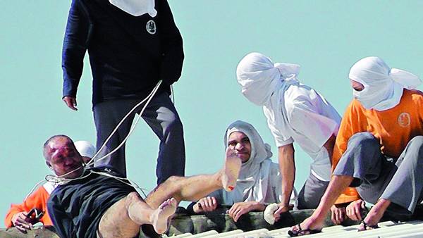 Techos. Un grupo de presos en el penal, con uno de los guardiacárceles tomados de rehén, el domingo. /AFP