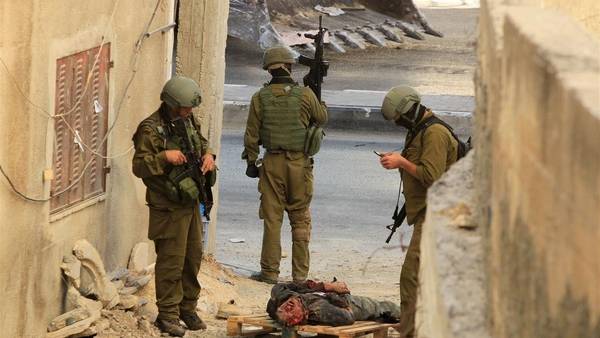 Soldados israelíes, junto al cuerpo de uno de los sospechosos de la muerte de tres chicos judíos en Hebrón, Cisjordania. (AFP)