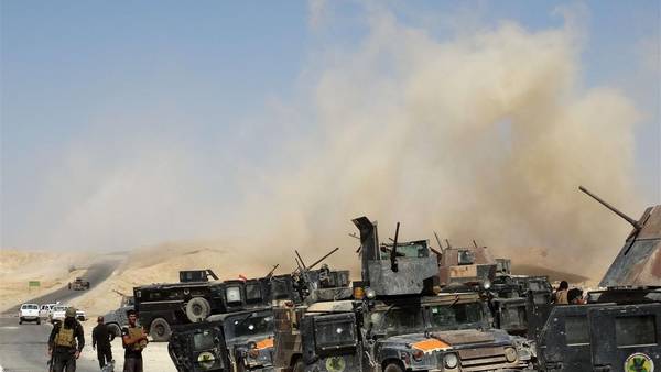 Soldados iraquíes, junto a sus vehículos, ante una cortina de humo tras disparar una ronda de morteros, en la provincia de Anbar. (AFP)