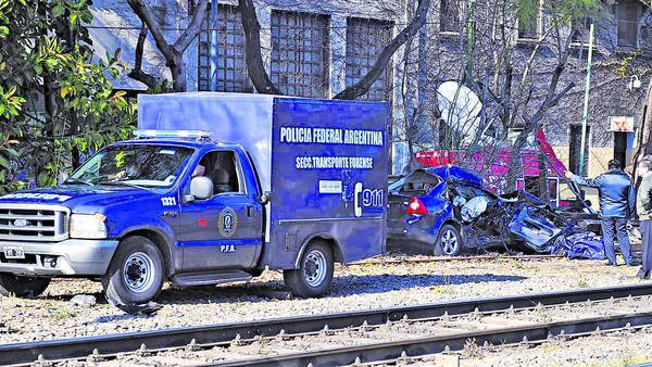 Tragedia. El auto arrollado detrás de la camioneta de la morgue. El tren lo arrastró varios metros. Los vecinos dicen que el paso a nivel es peligroso y las señales son confusas. /ALFREDO MARTINEZ