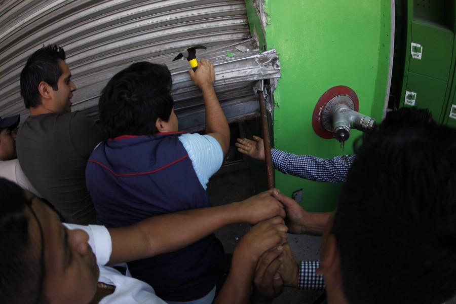 Supermarket employees try to fix a roller shutter at their workplace, which was damaged by Ayotzinapa Teacher Training College students, in Chilpancingo, in the Mexican state of Guerrero