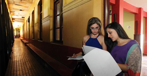 Una arquitecta, de pie en el ingreso del teatro del antiguo colegio, recibe la explicación sobre los ambientes que podrán ser modificados