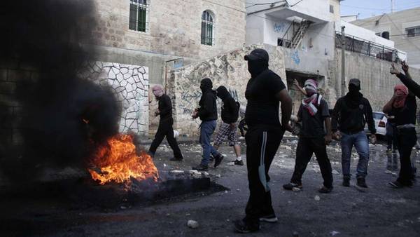 Palestinos enmascarados chocan con fuerzas de seguridad israelíes en el barrio árabe de Jerusalén este Abu Tor.