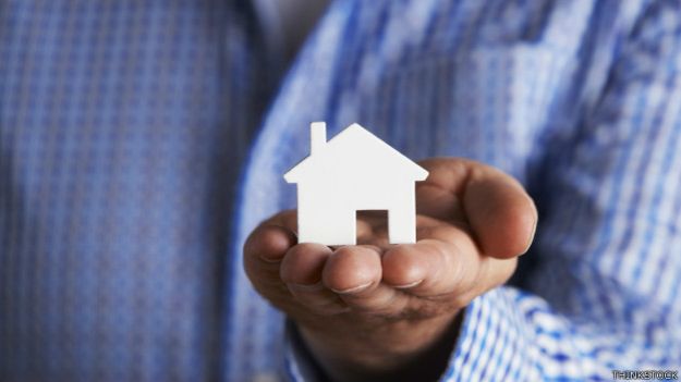 Un ejecutivo con un modelo de una casa en la mano