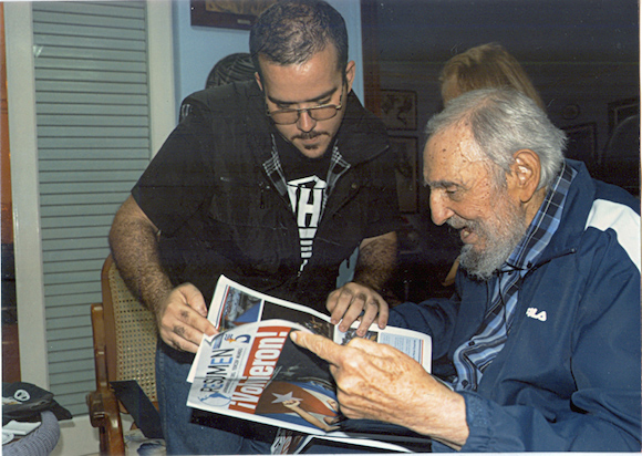 Former Cuban President Fidel Castro and President of Cuba's University Students Federation Randy Perdomo look at a newspaper during a meeting in Havana