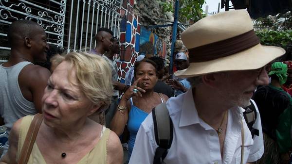 Turistas vistan el callejo de Hamel, mientras una cubana fuma un cigarro, en La Habana. /AP