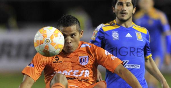 Jorge Cuéllar intenta proteger el balón mientras es encimado por el argentino Álvarez del equipo de Tigres