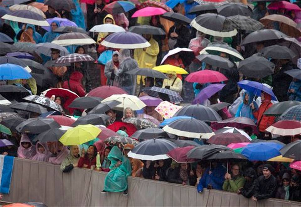 Los fieles esperan bajo la lluvia por la llegada del papa Francico para decir la misa del Domingo de Pascua en la Plaza de San Pedro en el Vaticano, el domingo 5 de abril de 2015.