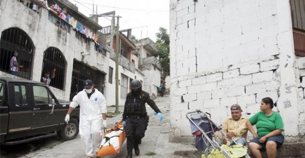 Una familia mira a los técnicos forenses y policías quitar un cuerpo de una escena del crimen en el barrio Independencia, en Monterrey