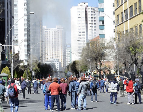 Una columna de humo, producto de un incendio en una delegación internacional cercana al Viceministerio de Gobierno, en la avenida Arce es observada por mineros cooperativistas