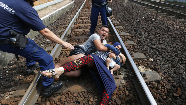 Video: Refugiados sirios se aferran con un bebé a las vías del tren para evitar que los deporten