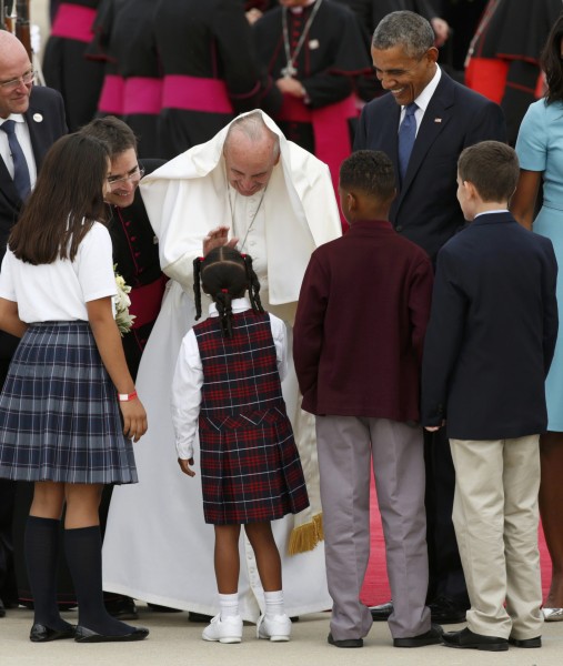 Pope Francis has part of his vestments get moved up to the back of his head by the wind as he greets children upon his arrival as he is welcomed by U.S. President Barack Obama (R) at Joint Base Andrews outside Washington September 22, 2015. REUTERS/Kevin Lamarque (TPX IMAGES OF THE DAY)