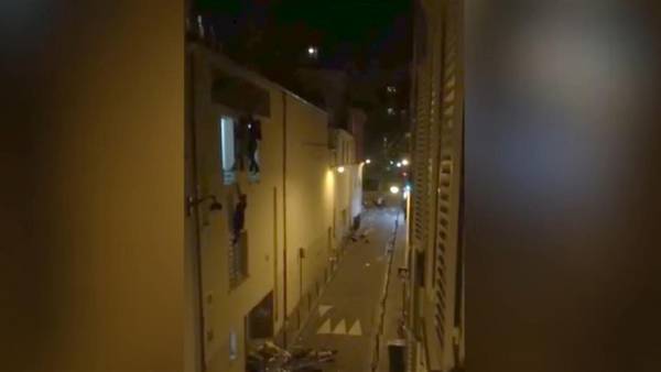 Una mujer cuelga de una ventana del segundo piso del teatro parisino de Bataclan, en medio del ataque terrorista.