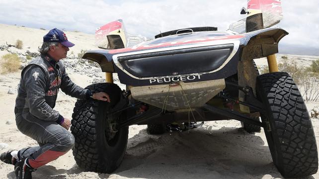 Carlos Sainz observando su Peugeot tras abandonar el Dakar. Foto: Reuters