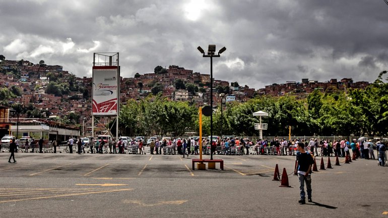 Decenas de venezolanos esperan en fila para ingresar a un supermercado en Caracas