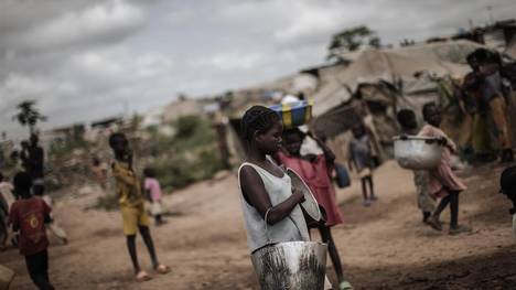 Una joven espera cargar su ración diaria de agua en el campo de desplazados de Mpoko, en Bangui. / AFP
