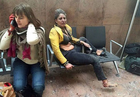 Nidhi Chaphekar, de chaqueta amarilla, aparece cubierta de polvo tras un ataque terrorista en Bruselas. En medio del caos, una mujer habla por su teléfono celular.