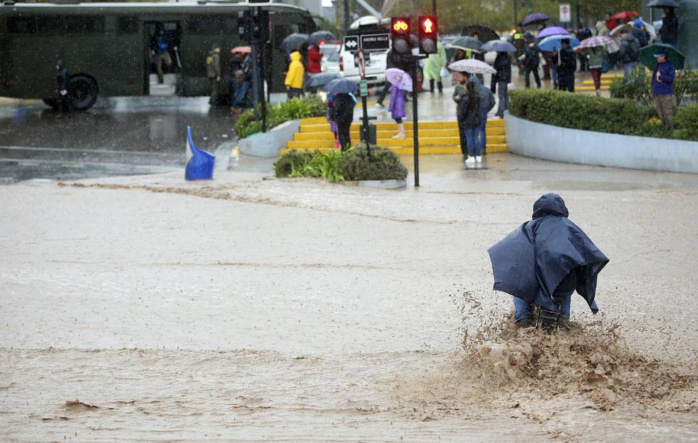 Un hombre cruza una calle inundada en Santiago de Chile.