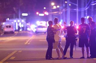 Agentes de policía de Orlando hablan con familiares en un tiroteo múltiple en un club nocturno en Orlando, Florida.