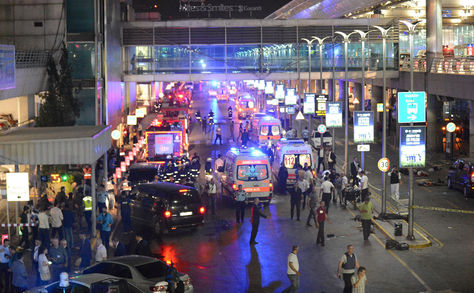 Esta imagen obtenida de la agencia de noticias Ilhas muestra ambulancias y policías creando un perímetro, al lado de gente tirada en el suelo (der.), después de dos explosiones seguidas de disparos en el mayor aeropuerto de Turquía en Istabul.