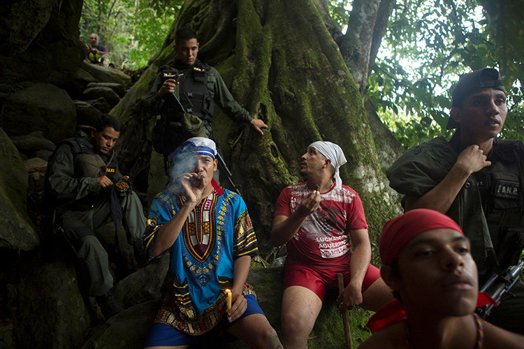 Creyentes fuman cigarros junto a la Guardia Nacional de Venezuela en el santuario de María Lionza , Venezuela 11 de octubre de 2015. REUTERS / Marco Bello 