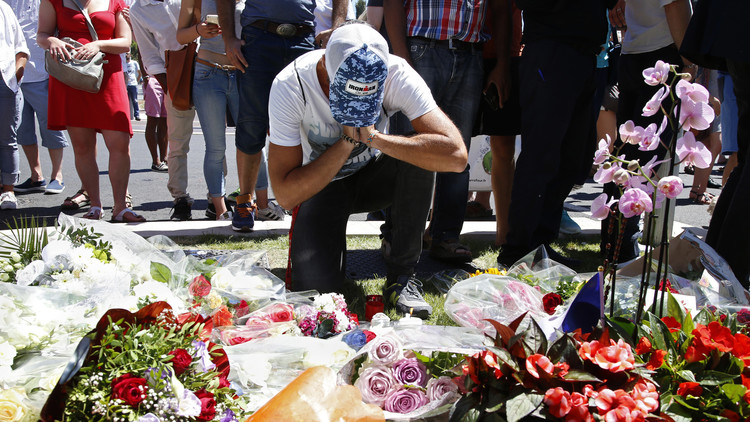 Un hombre ante ramos de flores, mientras la gente se congrega para homenajear a las víctimas del atentado en Niza, 15 de julio de 2016.
