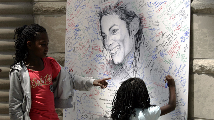 Dos fanáticos de Michael Jackson firman un cartel del cantante en Detroit después de su funeral.  7 de julio de 2009.