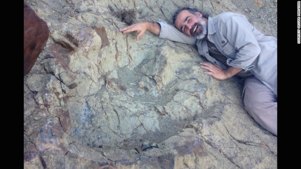 El paleontólogo Sebastián Apesteguia posa junto a la inmesa huella fosilizada. (Crédito: Grover Marquina).