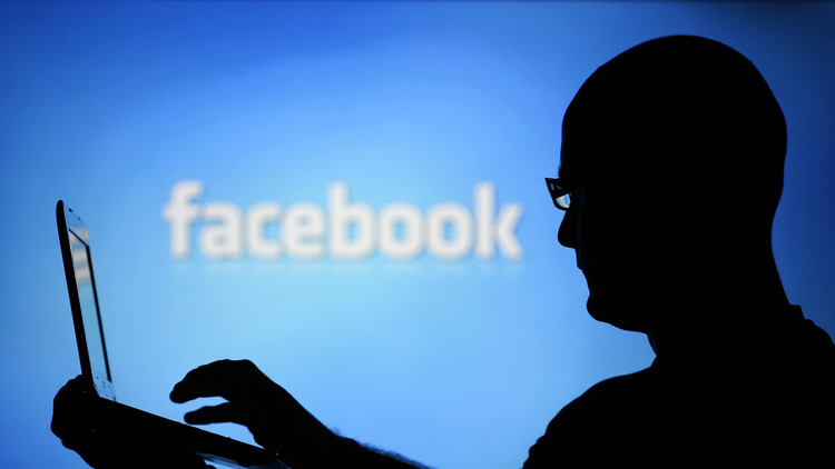 La silueta de un hombre con una portátil vista sobre una pantalla con un logotipo de Facebook, Zenica, Bosnia y Herzegovina