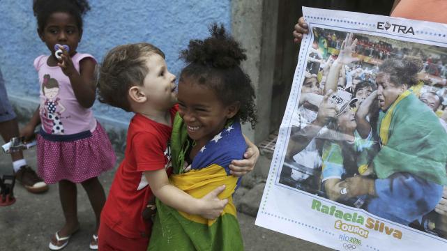 Niños de la favela donde nación Rafaela Silva, que se la ve en la portada de un diario. Foto: Reuters %image_alt%