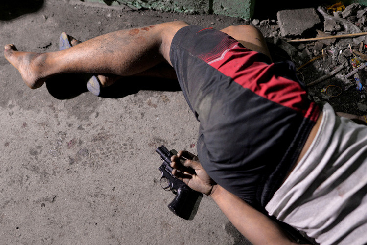El cuerpo de un hombre con una pistola bajo su mano, quien según la policía murió durante un operativo de incautación de droga en Manila, Filipinas