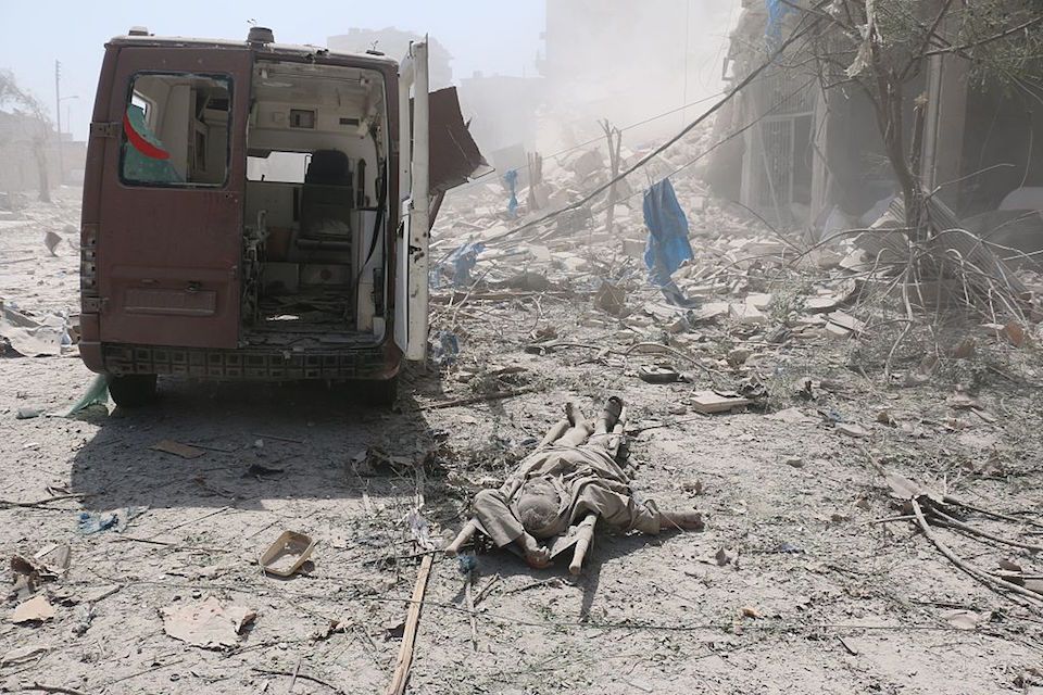 EDITORS NOTE: Graphic content / A corpse lies behind a damaged ambulance in the Maadi district of eastern Aleppo after regime aircrafts reportedly dropped explosive-packed barrel bombs on August 27, 2016. At least 15 civilians were reported killed when two bombs fell several minutes apart, near a tent where people were receiving condolences for those killed this week. / AFP / AMEER ALHALBI (Photo credit should read AMEER ALHALBI/AFP/Getty Images)