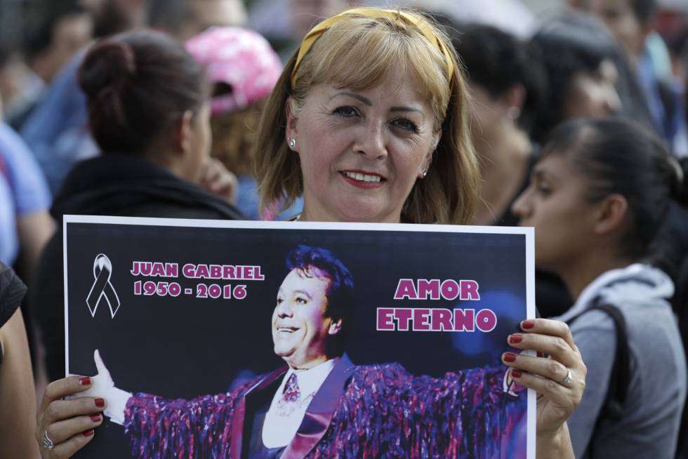 Una mujer sostiene un póster de Juan Gabriel en México. Una mujer sostiene un póster de Juan Gabriel en México.