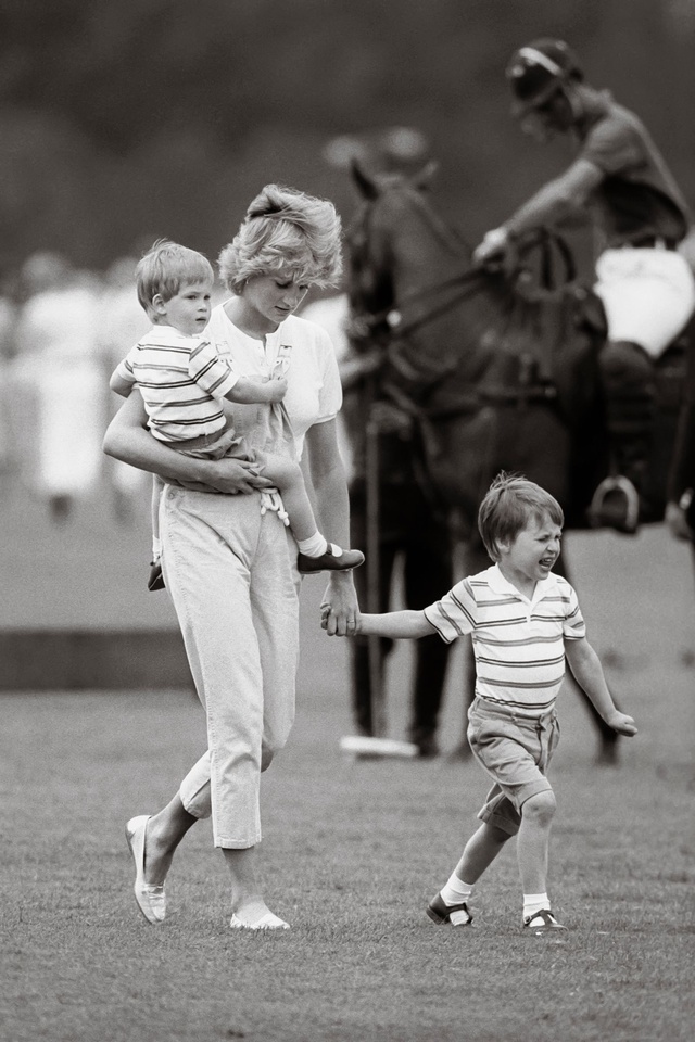 Diana con el príncipe Harry en brazos (y Guillermo de la mano) en un partido de polo.